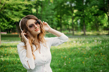 Music for work, Concentration and relax. Young business woman in headphones enjoys music in city park, outdoor portrait of young business woman in headphones