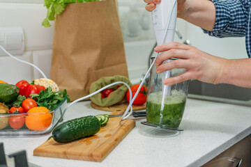 Green cucumber Smoothies for Weight Loss. Plus size woman making a cucumber cocktail. Female hand holding in hand glass with slimming Green Smoothie, juice