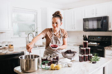 Fototapeta na wymiar Woman canning homemade blackberry jam in home kitchen