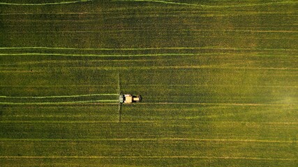 Birds-eye view of a tractor working in a green field © Martin Stoychev/Wirestock