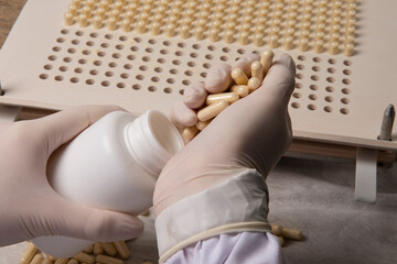 pharmacy professional placing medicine capsules produced in packaging