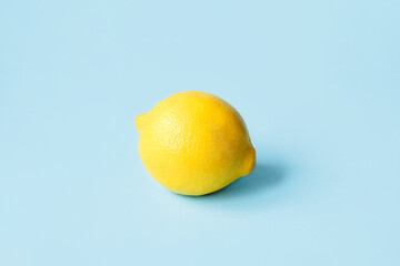 One ripe lemon on a blue background. Minimal summer concept.