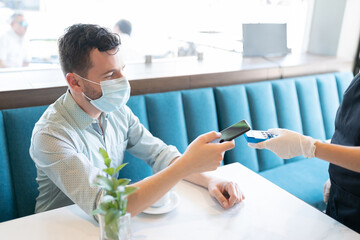 Man Paying Through Smartphone In Cafe