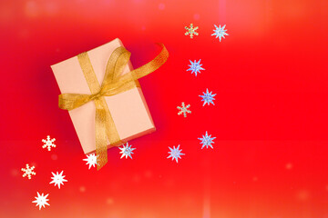 Bright red background with a festive box and gift, gold ribbon, shiny stars.