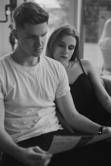 Couple on the couch black and white photo, stylish photo of love. Fashion photo of a couple, blonde girl with a guy. Perfume, love is in the air.