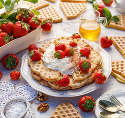 Waffles with whipped cream and fresh strawberries on a white plate