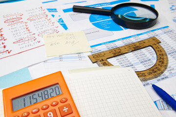 business office desk closeup - financial reports, analysis and accounting, set of documents, tables and graphs, various items for bookkeeping, calculator