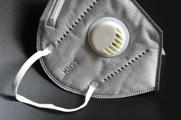 KN95 or N95 mask with valve for protection pm 2.5 and corona virus on black background. Prevention of the spread of virus and pandemic COVID-19.