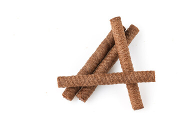 Heap of chocolate waffle rolls isolated on white background with shadows and grit. Close-up