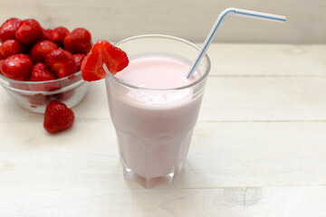 Strawberry smoothie in glass with strawberries on white background.
