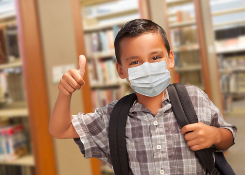 Hispanic Student Boy Wearing Face Mask with Thumbs Up and Backpack in the Library