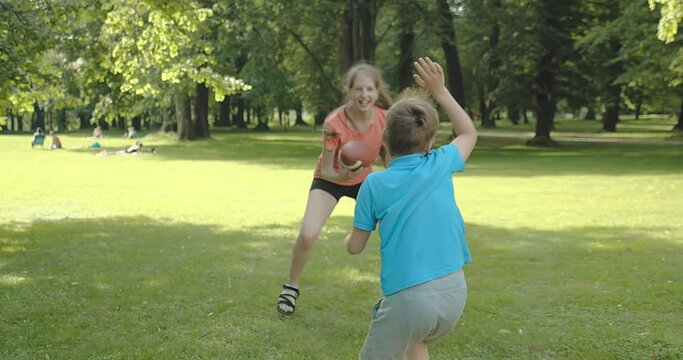 Father and children playing football, Father's day, Playful Man teaching son and daughter rugby outdoors in sunny day at public park. Family sports weekend. 4K video