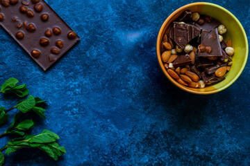 Chocolate chunks with hazelnuts isolated on blue background
