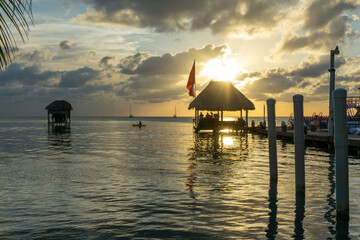 Ocean hut above water under a gold sunset with reflective shinny water