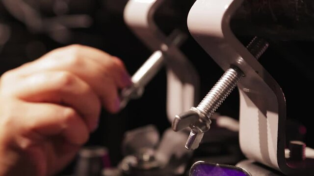A female hand fastens a screw on a soffit hanging on a shank