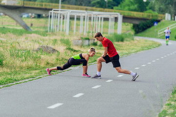 Young couple  warming up and stretching together in a park before running