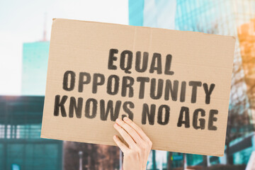 The phrase " Equal opportunity knows no age " on a banner in men's hand with blurred background. Equality on workplace. Office. Job. Employment. Work. Human rights. Difference. No discrimination
