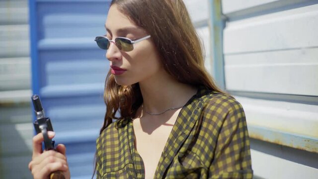 pretty mexican woman with glasses, with a revolver, aiming at the camera. pointed a gun at the camera, on the street