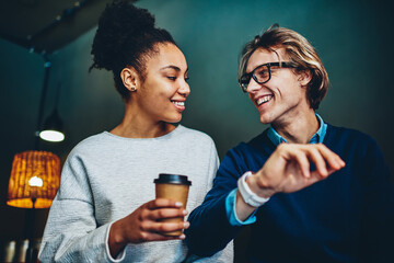 Happy multiracial marriage talking to each other smiling enjoying spending time together indoors,cheerful african american woman looking at her boyfriend communicating holding coffee to go cup.