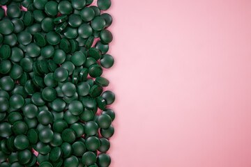 Spirulina pills on a pink background