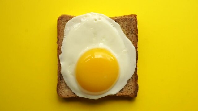 Toast with fried egg on a yellow background. Toast (sandwich) for breakfast, minimal food concept.
