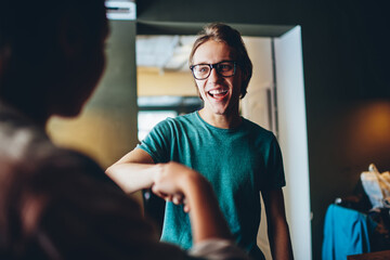 Happy caucasian man in spectacles excited with meeting colleague greeting with handshake indoors,...