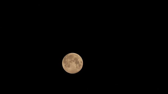 A Time-lapse video of penumbra lunar eclipse full moon shining bright in dark night sky observed through telescope