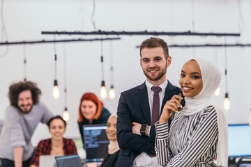 Portrait of a formal businessman and young African American businesswoman posing with their team in a modern startup office. Marketing concept. Multi-ethnic society..