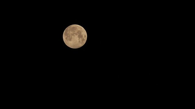 A Time-lapse video of penumbra lunar eclipse full moon shining bright in dark night sky observed through telescope