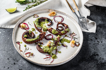 Cooked octopus tentacles with pesto, thyme and onion. Black background. Top view
