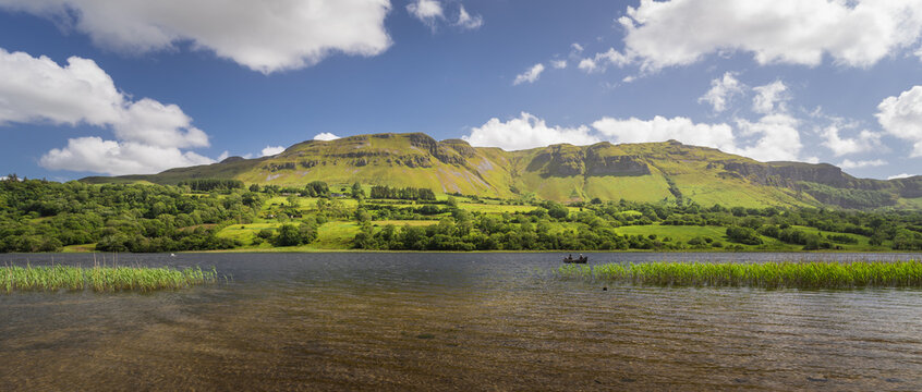 Glencar Lough, Leitrim, Ireland.  A couple of fisherman are fishing on a boat in the middle of the lake at the foot of the mountains.