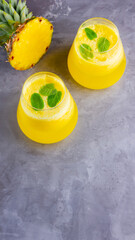 Pineapple cocktail on a gray background. Cold pineapple cocktail with mint. Summer tropical cocktail. Healthy drink. Top view. Copy space