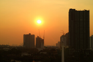 Dazzling sun on the golden sky over the silhouette of construction site