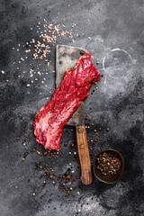 Raw strip vegas steak on a meat cleaver. Black background. Top view