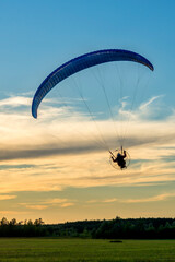 A powered paraglider flying at sunset. Silhouette of moto paraglider (motoparaplan) on a summer sky