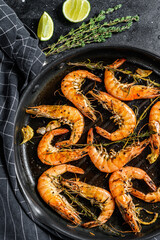 Fototapeta na wymiar Grilled giant langoustine shrimps, prawns in a frying pan. Black background. Top view