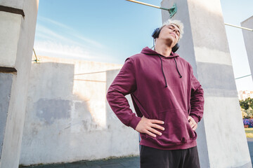 Sportsman warms up, doing neck rotation exercises and listening to music in headphones