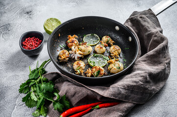 Grilled cuttlefish with lime and spices in a pan. Gray background. Top view