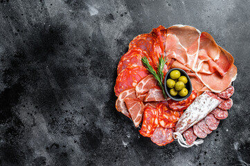 Spanish cold meat assortment. Chorizo, fuet, LOMO, jamon Iberico, olives. Black background. Top view. Copy space
