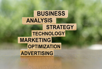 Wooden blocks stacked on top of each other to build a business strategy with analysis, strategy, technology, marketing, optimization, advertising