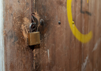 An old worn padlock on a vintage wooden door