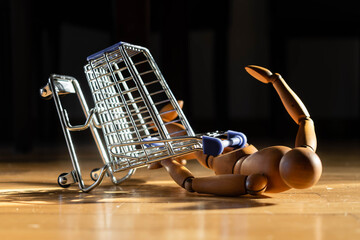 caída de carro de supermercado y muñeco de madera sobre piso parket