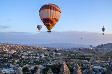 Fototapeta na wymiar Color hot air balloons flying at sunrise over stone formations in valley of Cappadocia,Turkey