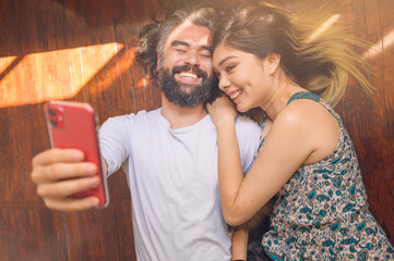 Couple lying on the living room floor in romantic moment taking a selfie