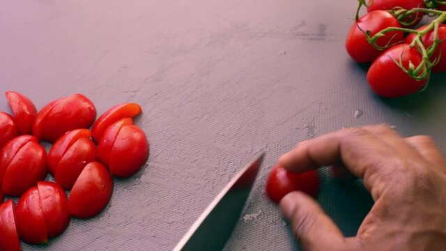 Chef preparing cherry tomatoes for vegetarian dish in kitchen