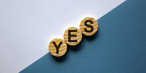 Wood circles with word 'yes' stacking as step stair on paper white and blue background, copy space....