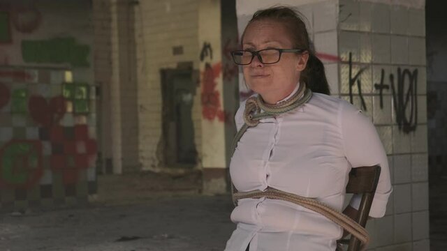 Exhausted woman hostage examines room where is in captivity.