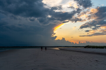 Dark Clouds at Sunset on Beach with two people silhouettes