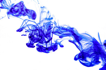 Blue ink injected into water from syringe, colour mixing with water creating abstract shapes