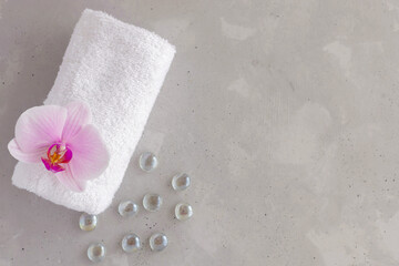 Concept for spa salon, face and body care, massage room or beautician. White bath towel and orchid. Copy space